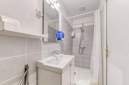 Un baño blanco con lavabo y ducha. en Hôtel Vila, en Frontignan