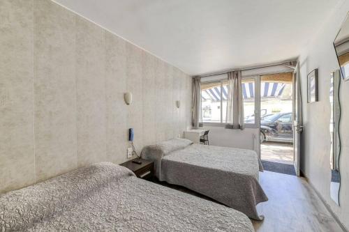 una habitación con dos camas y una ventana en Hôtel Vila, en Frontignan