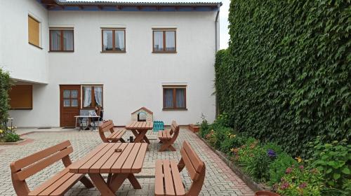a patio with wooden tables and chairs in front of a building at Appartementhaus Lang in Mörbisch am See