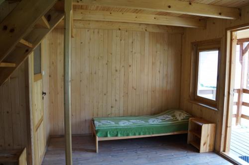 a bed in a wooden room with a window at Owk Korona in Mikoszewo
