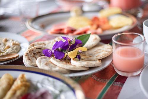 una mesa con platos de comida y un vaso de zumo de naranja en Welikande Yoga Retreats, en Digana