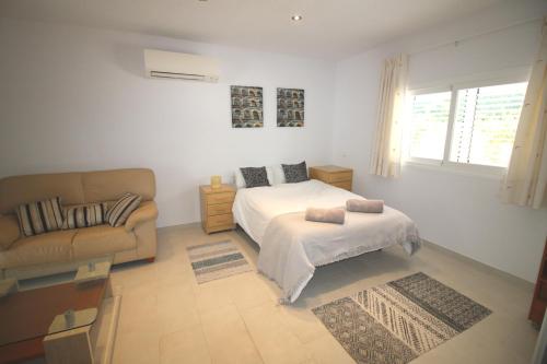 a white bedroom with a bed and a couch at Villa Sunset - San Antonio Bay in Cala de Bou