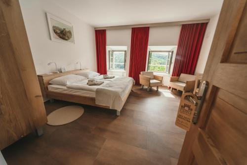 a bedroom with a bed and a chair and windows at Rooms & Apartments Podsreda Castle in Podsreda