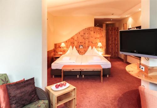 a hotel room with a bed and a flat screen tv at Der Kirchheimerhof - Superior in Bad Kleinkirchheim