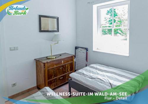 ein Schlafzimmer mit einem Bett, einer Kommode und einem Fenster in der Unterkunft Wellness-Suite-im-Wald-am-See in Kyritz