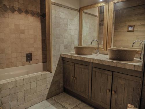 een badkamer met 2 wastafels en een bad bij Le Cairn in Peisey-Nancroix