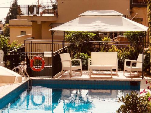 a patio area with a pool, chairs and umbrellas at Hotel Soleado in Taormina