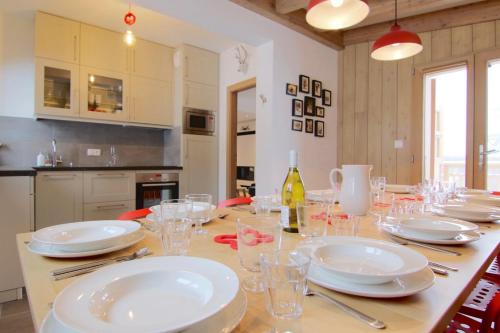 - une table à manger avec des assiettes blanches et des verres dans l'établissement Le Chalet, à Peisey-Nancroix