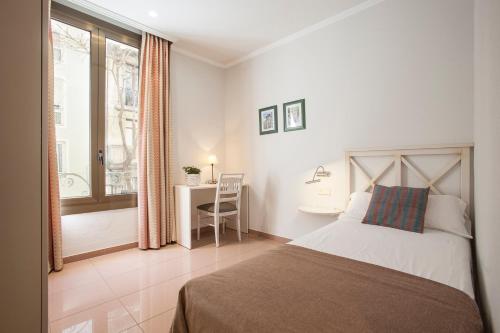 - une chambre avec un lit, un bureau et une fenêtre dans l'établissement BCNGOTIC 11, à Barcelone