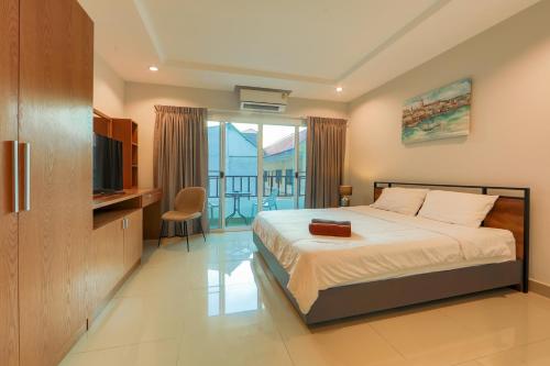 a bedroom with a bed with a television and a balcony at Nalanta Hotel Pattaya in Pattaya Central