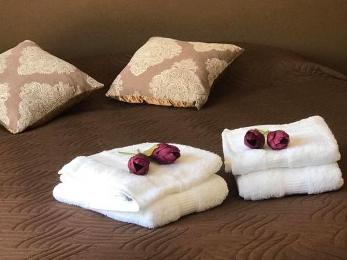two folded towels on a bed with two roses at Villa Maria Alvor in Alvor