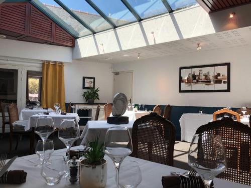 une salle à manger avec des tables blanches, des chaises et des verres dans l'établissement Auberge Saint Thegonnec, à Saint-Thégonnec