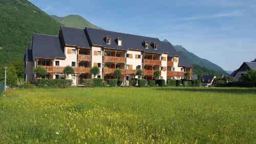 a large building with a green field in front of it at Résidence Val de Roland in Luz-Saint-Sauveur