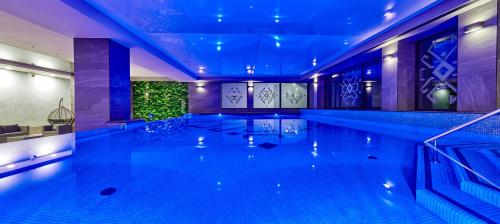 a swimming pool with blue lights in a building at ibis Styles Nowy Targ in Nowy Targ