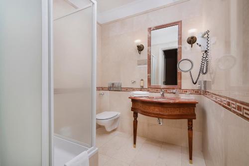 a bathroom with a sink and a toilet and a mirror at IBB Hotel Grand Hotel Lublin in Lublin