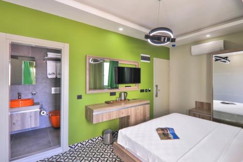 a bathroom with a green wall with a sink and a mirror at Zeytin HOTEL in Kaş