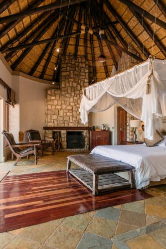 a bedroom with a bed and a fireplace at Shumbalala Game Lodge in Thornybush Game Reserve