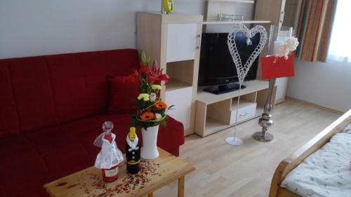 uma sala de estar com um sofá vermelho e uma mesa com flores em Südtiroler Stubn Café und Restaurant em Arnstadt