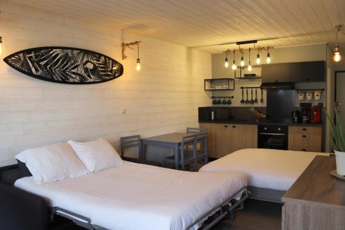 a room with two beds and a table and a kitchen at Atlantic Selection - Le studio 48 in Capbreton