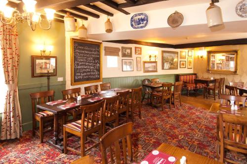 um restaurante com mesas e cadeiras de madeira e um quadro-negro em The George & Horn near Newbury em Kingsclere