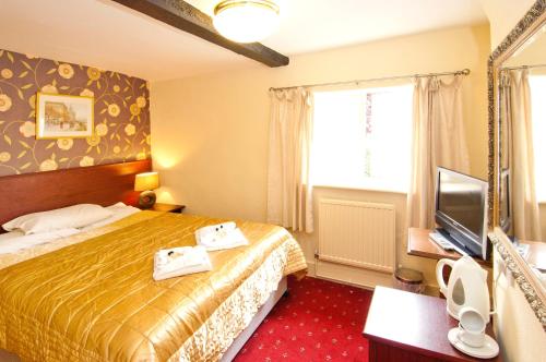 um quarto de hotel com uma cama e uma televisão em The George & Horn near Newbury em Kingsclere