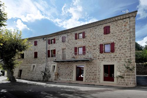 Sanilhac的住宿－Chambre d'hôte avec jacuzzi，一座带红色门和阳台的大型砖砌建筑
