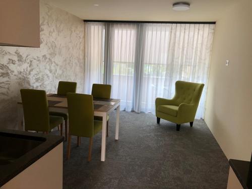 a dining room with a table and green chairs at wohnMOTEL - Hinterforst in Altstätten