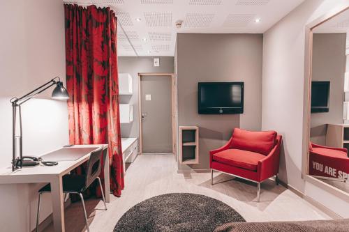 a room with a red chair and a desk and a tv at Centro Hotel Turku in Turku