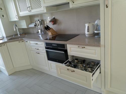 eine Küche mit weißen Schränken und einem Herd mit Backofen in der Unterkunft Baltieji apartamentai in Palanga