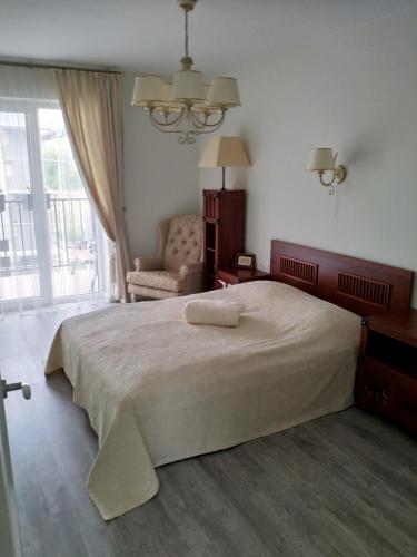 ein Schlafzimmer mit einem großen Bett und einem Stuhl in der Unterkunft Baltieji apartamentai in Palanga