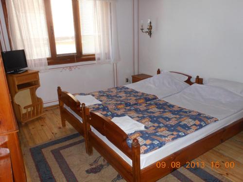 a bedroom with a bed and a television and a window at Family Hotel Kalina in Koprivshtitsa