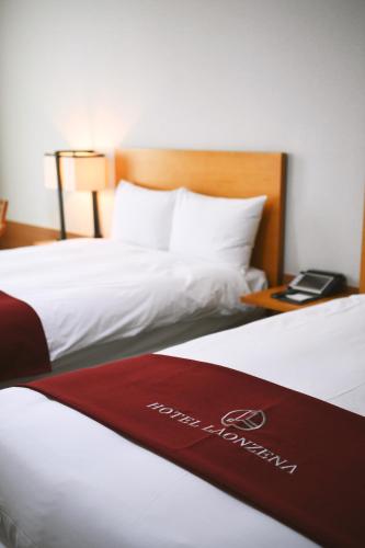 two beds in a hotel room with a red sign on them at Hotel Laonzena in Daegu