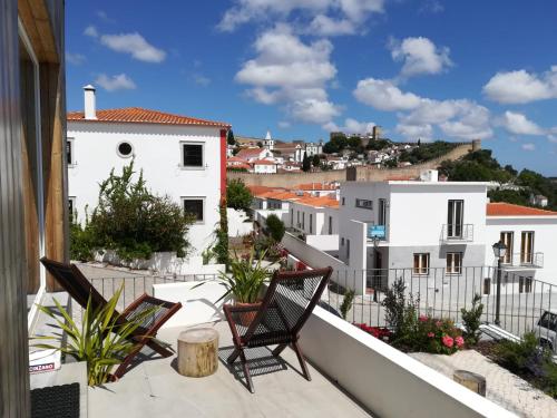 a balcony with chairs and a view of buildings at adubai Obidos in Óbidos