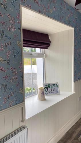 a window sill in a room with a flowery wallpaper at Toddys Cottage & Stables in Cavan