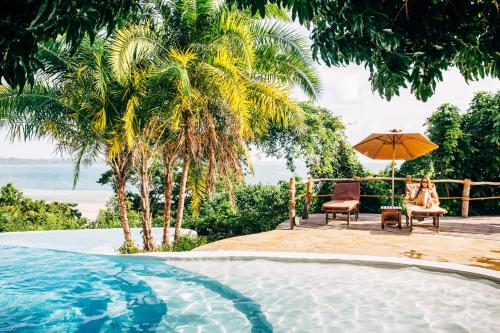 une femme assise sur une chaise à côté d'une piscine dans l'établissement Fundu Lagoon, à Pemba