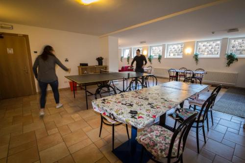 two people walking in a room with tables and chairs at Casa per Ferie Le Rais in Pozza di Fassa