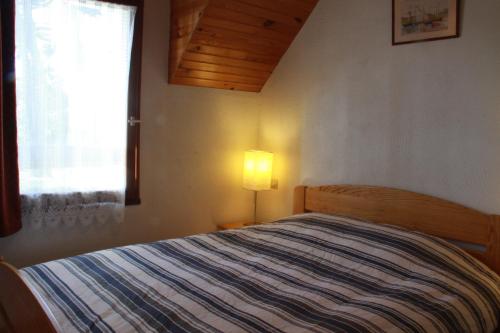 a bedroom with a bed with a lamp and a window at Maison à 200 m de la mer in Piriac-sur-Mer