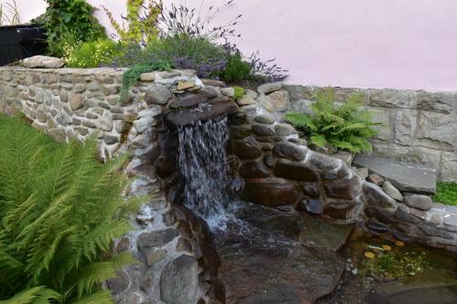 a waterfall in a stone wall in a garden at Lovecký Apartmán na náměstí ve Frenštátě pod Radhoštěm in Frenštát pod Radhoštěm