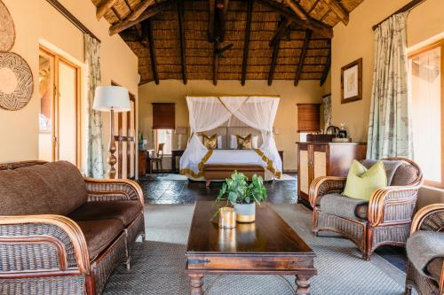 a living room with a bed and a couch and a table at Thornybush Jackalberry Lodge in Thornybush Game Reserve