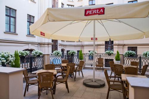 a patio with tables and chairs and an umbrella at IBB Hotel Grand Hotel Lublin in Lublin