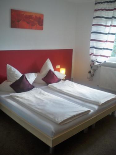 - un lit avec des draps et des oreillers blancs dans l'établissement Hotel zur Donau, à Dillingen an der Donau