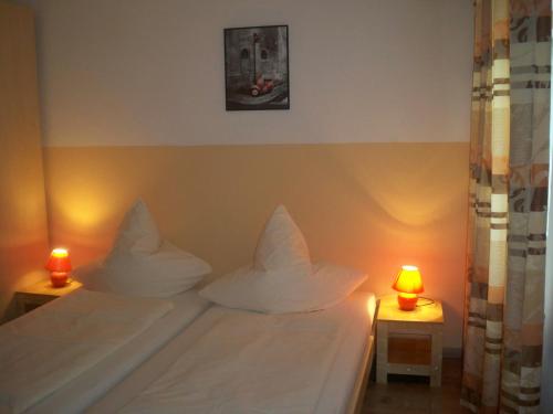 ein Schlafzimmer mit weißen Kissen und 2 Kerzen auf Tischen in der Unterkunft Hotel zur Donau in Dillingen an der Donau