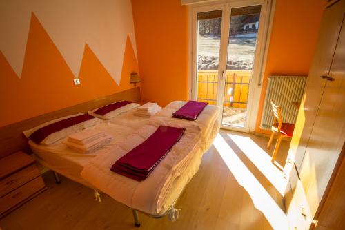 a large bed in a room with a large window at Casa per Ferie Le Rais in Pozza di Fassa