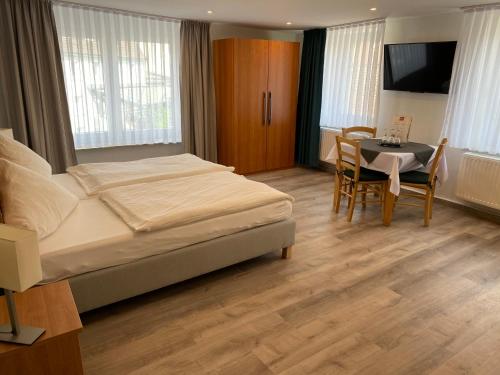 een slaapkamer met een bed, een tafel en een televisie bij Gästehaus Gisela in Bad Dürrheim