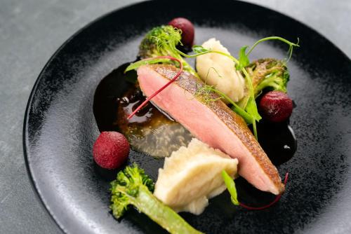 a black plate of food with broccoli and meat at IBB Hotel Grand Hotel Lublin in Lublin