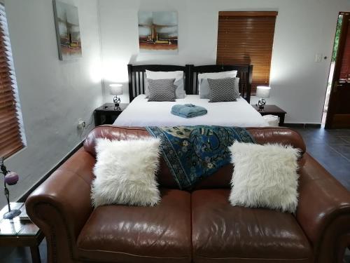 a bedroom with a bed and a brown leather couch at Joy on Joyce in Alberton