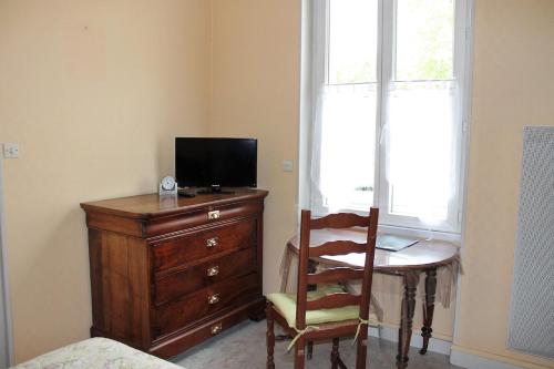 a bedroom with a desk with a television and a chair at Champêtre in Rochefort
