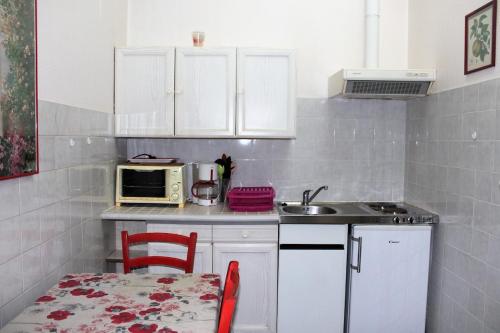 a kitchen with white cabinets and a table and a microwave at Champêtre in Rochefort