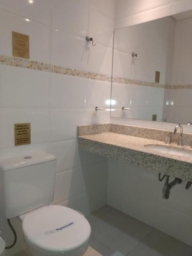 a white bathroom with a toilet and a sink at Hotel Hetropolis in São Bernardo do Campo