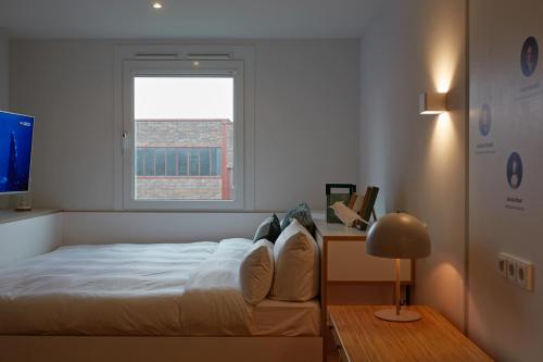 a bedroom with a bed with a window and a desk at hotel friends Essen Zeche Zollverein in Essen